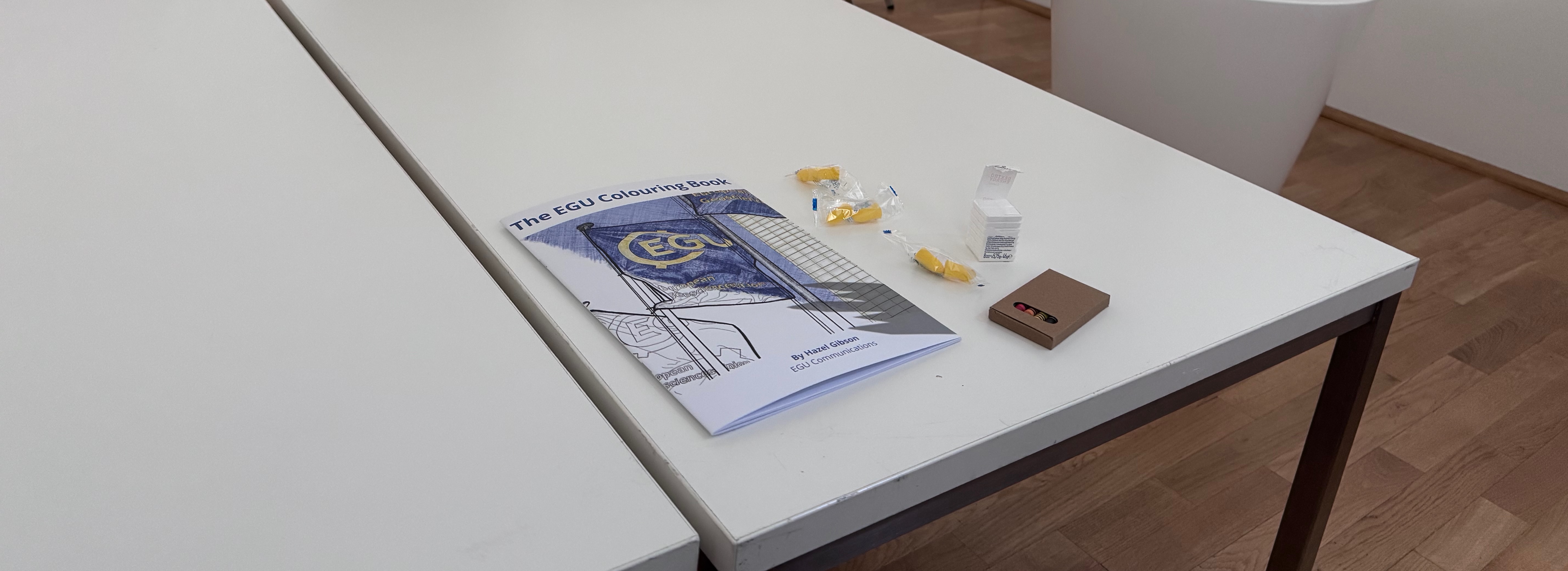 An EGU colouring book, crayons, earplugs, and dextrose tablets on a white table